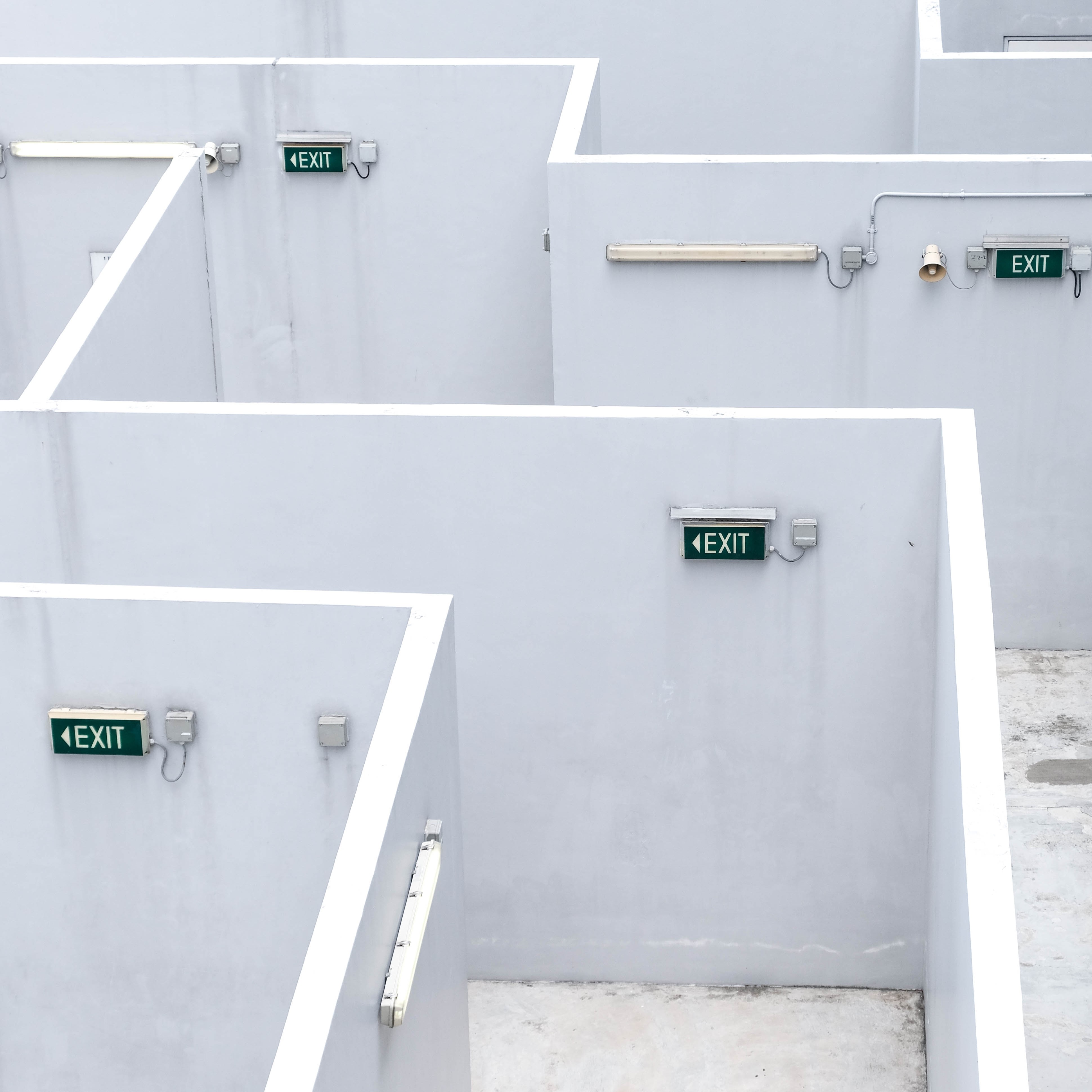 A white concrete maze with several black "exit" signs but no apparent way out.