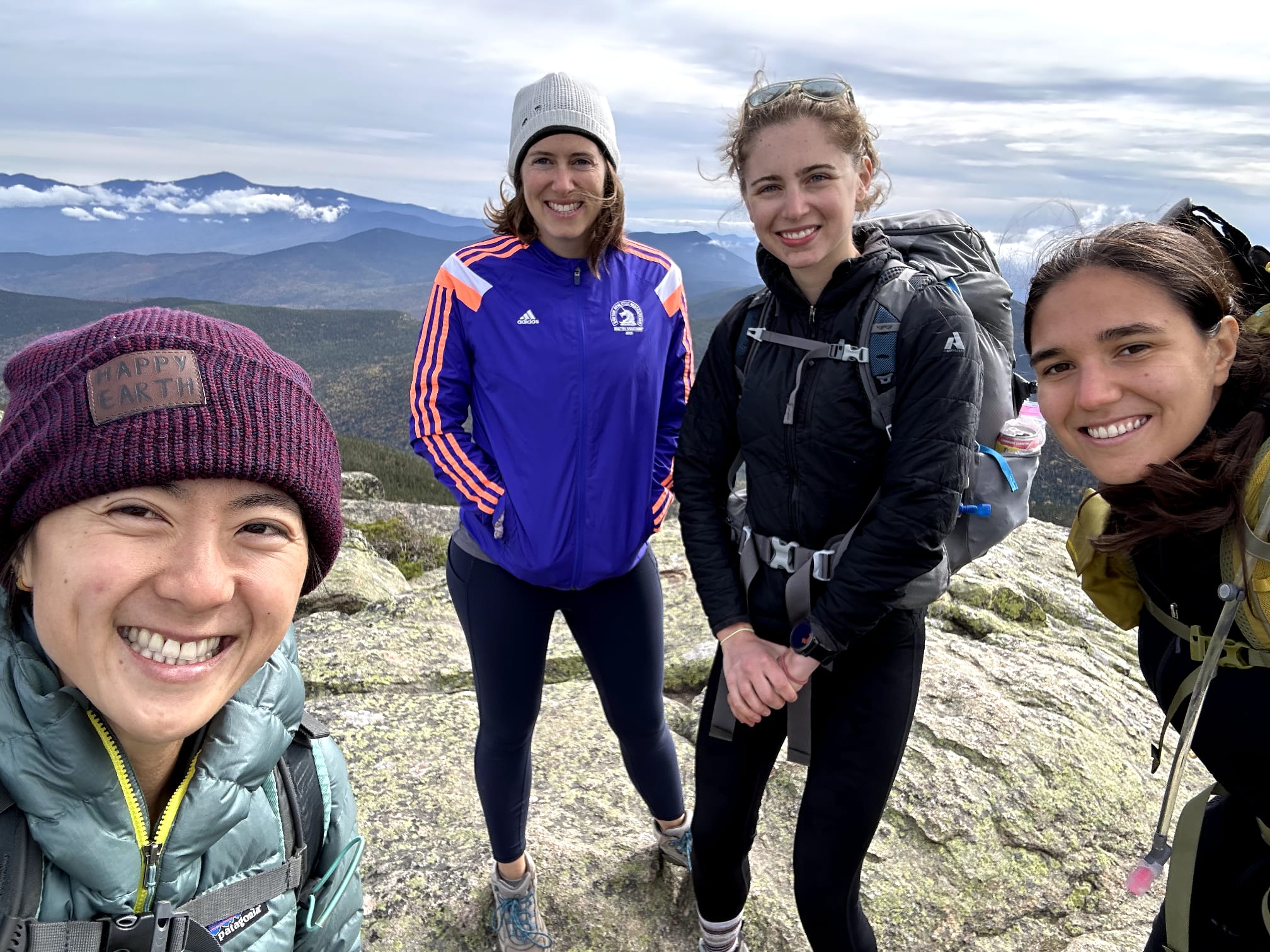 Four women on top of a mountain summit with mountains in the background